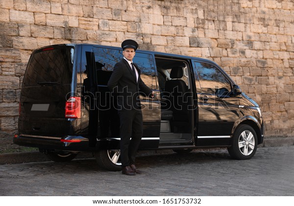 Driver opening door of luxury car on street.\
Chauffeur service