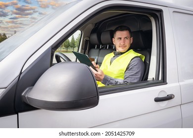 The Driver Plans To Work On The Tablet. Driver Driving A Cargo Van. Satisfied Man At Work. Delivery Of Parcels. The Postman Chooses The Delivery Route. Concept Of Logistics Services.