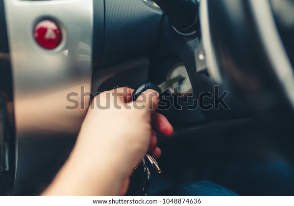 Driver plug in a key starting the engine of a car.\
The hand inserts the key into the ignition and starts right-hand\
drive car. Hand put the car key to the keyhole starting the car.\
Stylish Toned photo