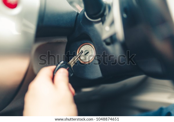 Driver plug in a key starting the engine of a car.\
The hand inserts the key into the ignition and starts right-hand\
drive car. Hand put the car key to the keyhole starting the car.\
Stylish Toned photo