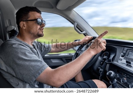 Driver pointing while driving. Man gestures in car. Reaction behind the wheel.
