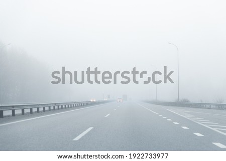 Driver POV of almost empty grey foggy misty rainy highway intercity road with low poor visibility on cold spring autumn morning. Seasonal bad rainy weather accident danger warning. car fog light