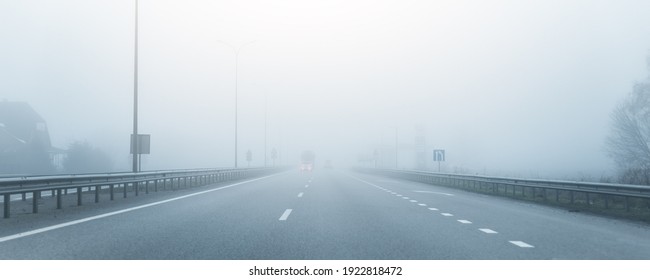 Driver POV on almost empty blue foggy misty rainy highway intercity road with low poor visibility on cold spring autumn morning. Seasonal bad rainy weather accident danger warning. car fog light - Powered by Shutterstock