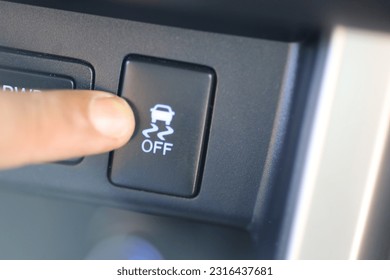 The driver presses the traction control button on the dashboard of the car.  modern car features to regulate traction on wheels