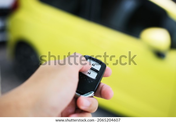 Driver\
pressing car alarm key and pointing it to his\
car
