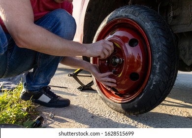 The Driver Puts The Spare Tire On The Car In The Middle Of The Road