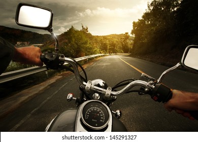 Driver riding motorcycle on an asphalt road through forest - Powered by Shutterstock