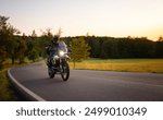 Driver riding motorcycle on empty road during sunset