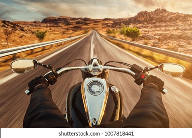 Driver riding motorcycle on an empty asphalt road - Shutterstock ID 1007818441