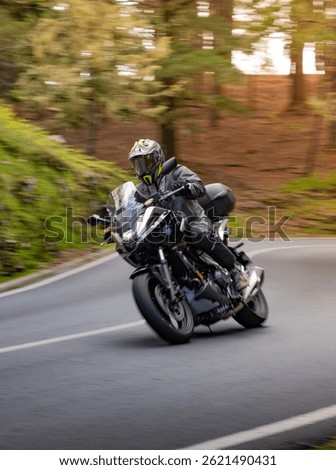 Driver riding motorcycle on empty asphalt road, blurred motiion, spring mountains