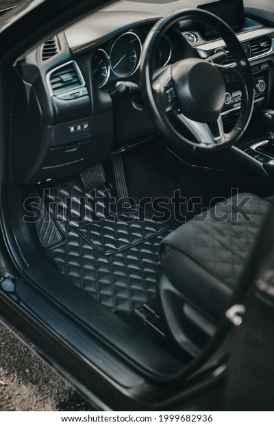 driver seat\
in the modern luxury car. luxury leather black floor mat. pedals,\
steering wheel and drivers cockpit. concept of luxury car\
protection and usage wear signs\
prevention.