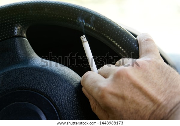 The driver smokes\
behind the wheel of a car during a traffic jam. Harmful and\
dangerous habits. Close-up.