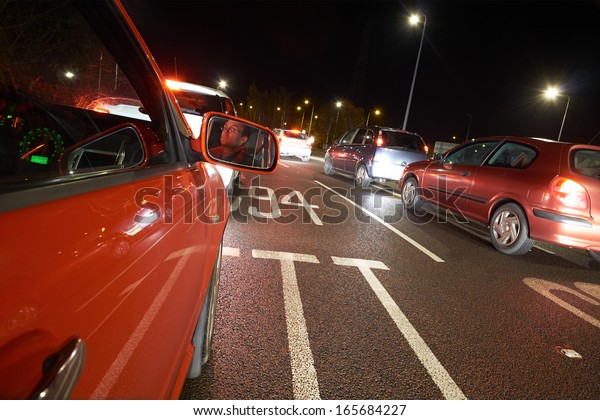 A\
driver stuck in a traffic jam on a busy road at\
night.