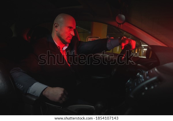 A\
driver in the suit is sitting by a car steering\
wheel.