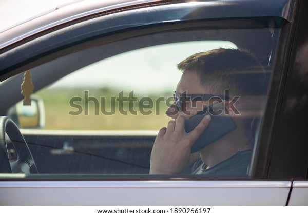 Driver is talking on the mobile phone close up.\
Side view.