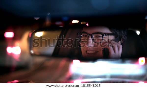 Driver talking on the phone,\
reflected in a rear view mirror, night shot. Driver in a mirror in\
car, night call on the road shot driving all night from\
backseat