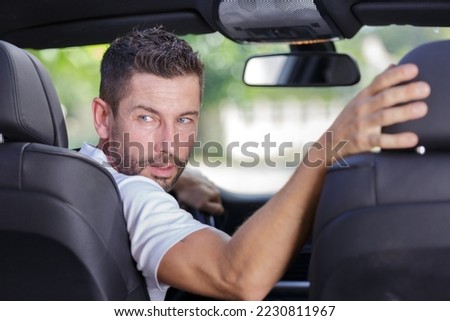 driver turning in his seat to look behind to reverse