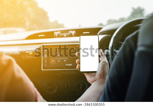 A driver uses a\
phone while driving on vacation a modern technology smartphone with\
a blank white screen.