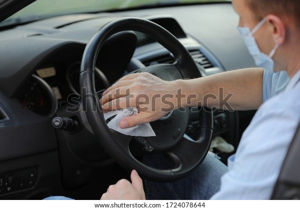 Driver using wet wipe for disinfecting car\
steering wheel against virus or Corona Virus Disease. car cleaning.\
selective focus.