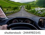 Driver view to the road with beautiful green landscape view from inside a car of driver POV. São Miguel island, Azores, Portugal, Europe.