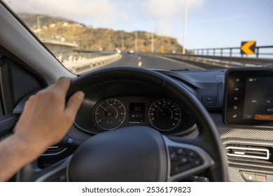 Driver view to the speedometer, with hand on the steering wheel. Blurred road bridge. Madeira island, Portugal.