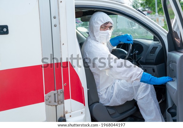 Driver wear PPE in front of the\
ambulance with protective suit, mask gloves at ambulance car\
vehicle for helping the patient of Coronavirus or Covid-19\

