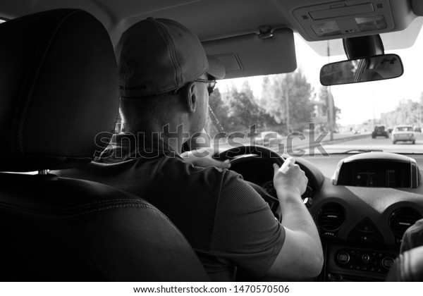 A driver with a wheel in his hands drives a car\
around the city.