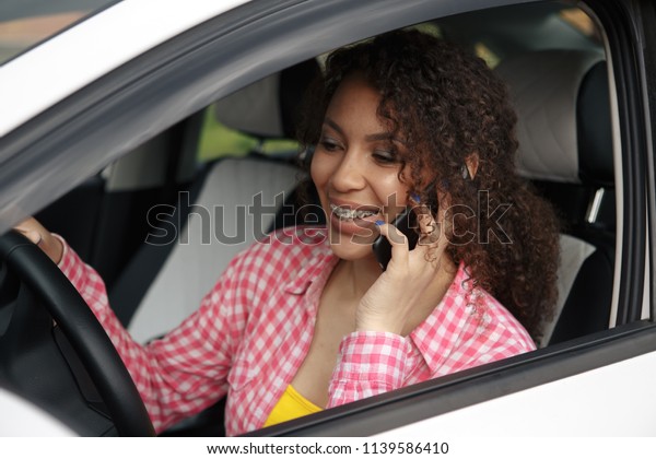 Driver woman driving a car distracted on the phone\
and looking at side