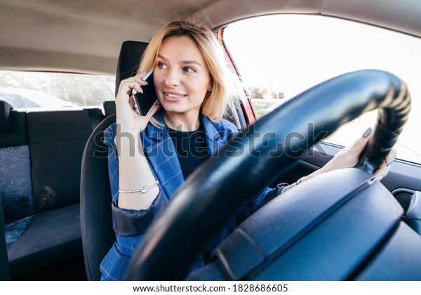 Driver woman driving a car distracted on the phone\
and looking at side