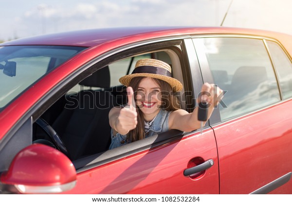 Driver woman\
smiling showing new car keys and car. Happy woman driver showing\
car keys and leaning on car\
door