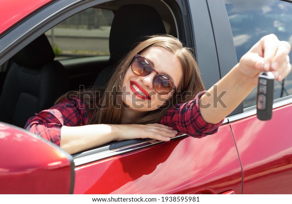 Driver woman\
smiling showing new car keys and car. Happy woman driver showing\
car keys and leaning on car\
door