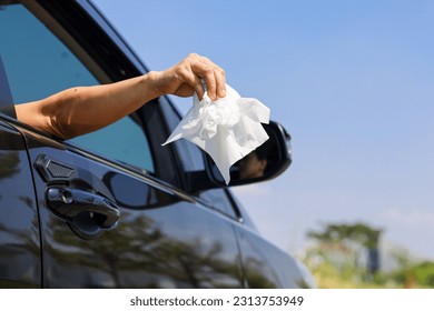 Driver's arm throws trash through car window on highway.  bad behavior concept on road.  Damaging the environment