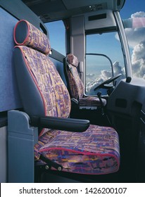 Driver's Compartment Of An Old Bus, Seat, Steering Wheel And Blue Sky, Clouds In The Background, Visible Through The Window.