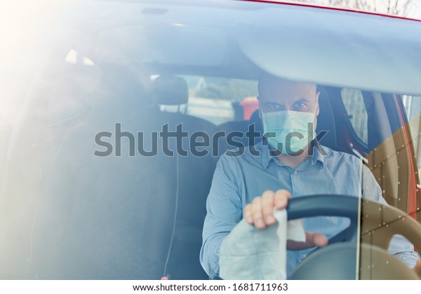 Drivers with face masks disinfect their\
steering wheel for fear of Covid-19\
coronavirus