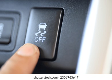 The driver's finger presses the Traction Control System button on the car's dashboard