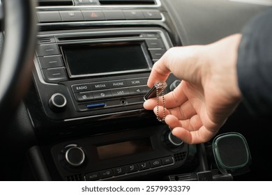 The driver's hand inserting a USB flash drive into the car's radio
