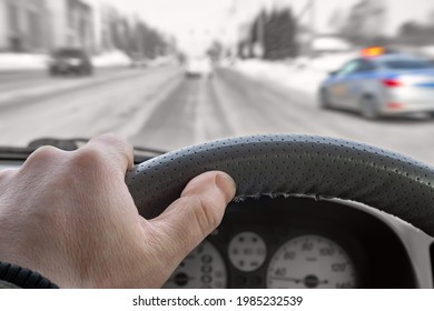 the driver's hand on the steering wheel inside the car against the background of the city road, traffic of cars and a police car with flashing lights, warning lights, standing on the side of the road