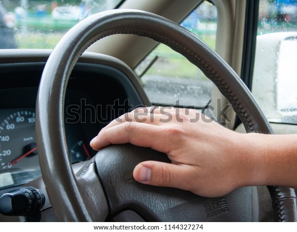 The driver\'s hand on the steering wheel of a\
car close-up.