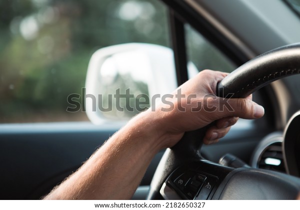 The driver\'s hand on the\
steering wheel of the car. Driving, traffic rules, safety at the\
wheel.