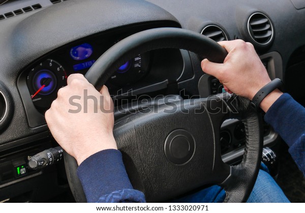 Driver\'s hands hold the steering\
wheel. Driving a car. Moving by car. The driver\'s hands are\
large