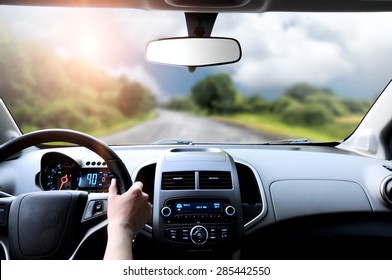 Driver's hands on the steering wheel inside of a car