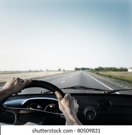 Driver's Hands On A Steering Wheel Of A Retro Car During Riding On An Empty Asphalt Road