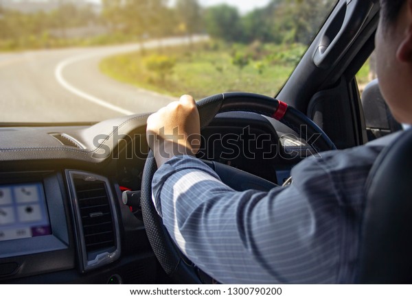 Driver\'s\
hands on the steering wheel inside of a\
car.
