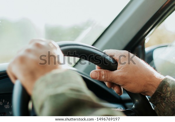  driver\'s hands on the steering wheel of a car.\
car driving
