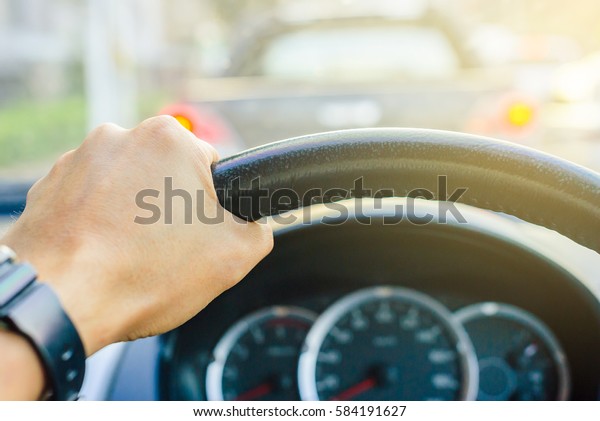 Driver\'s hands on the steering wheel inside\
of a car, Design for the\
background.