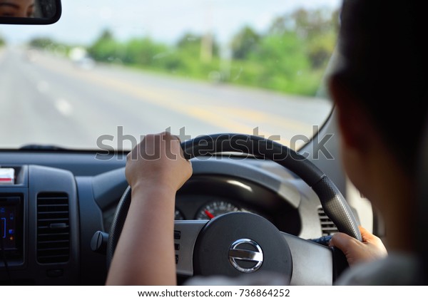 Driver\'s hands on steering wheel inside of a car,\
women driving