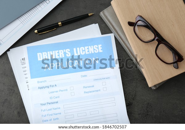 Driver\'s license application form, glasses and\
stationery on grey table, flat\
lay