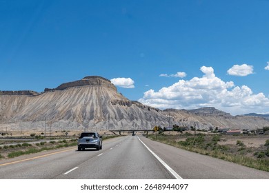 Drivers perspective over Interstate 70 with cars east of Grand Junction, CO, USA approaching Mt. Garfield and in background Mt. Lincoln with Mesaverde Group and Mancos Shale formations