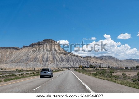 Drivers perspective over Interstate 70 with cars east of Grand Junction, CO, USA approaching Mt. Garfield and in background Mt. Lincoln with Mesaverde Group and Mancos Shale formations
