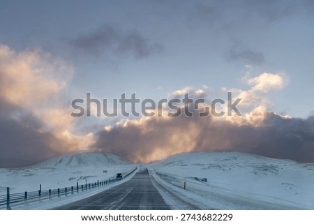 Drivers perspective  over main road around Iceland during winter with snow and dramatic clouds at sunsrise with blue sky
